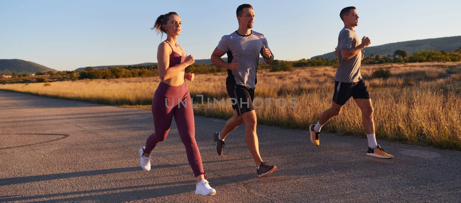 A group of young athletes running together in the early morning light of the sunrise, showcasing their collective energy, determination, and unity .