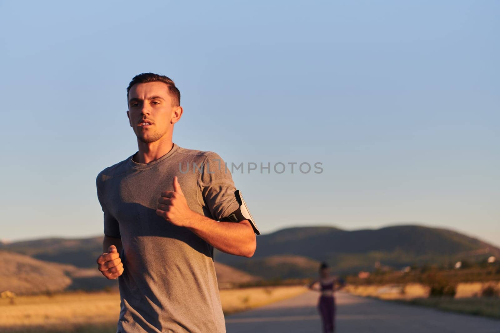 A handsome young couple running together during the early morning hours, with the mesmerizing sunrise casting a warm glow, symbolizing their shared love and vitality.