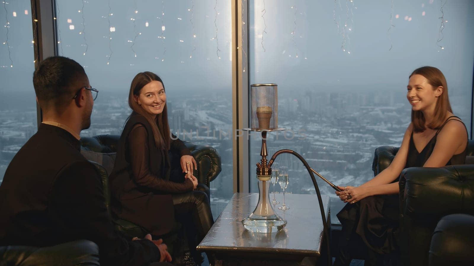 Man meets women in hookah bar. Media. Man sits down with young women to meet in restaurant. Company of elegant adults in hookah restaurant.