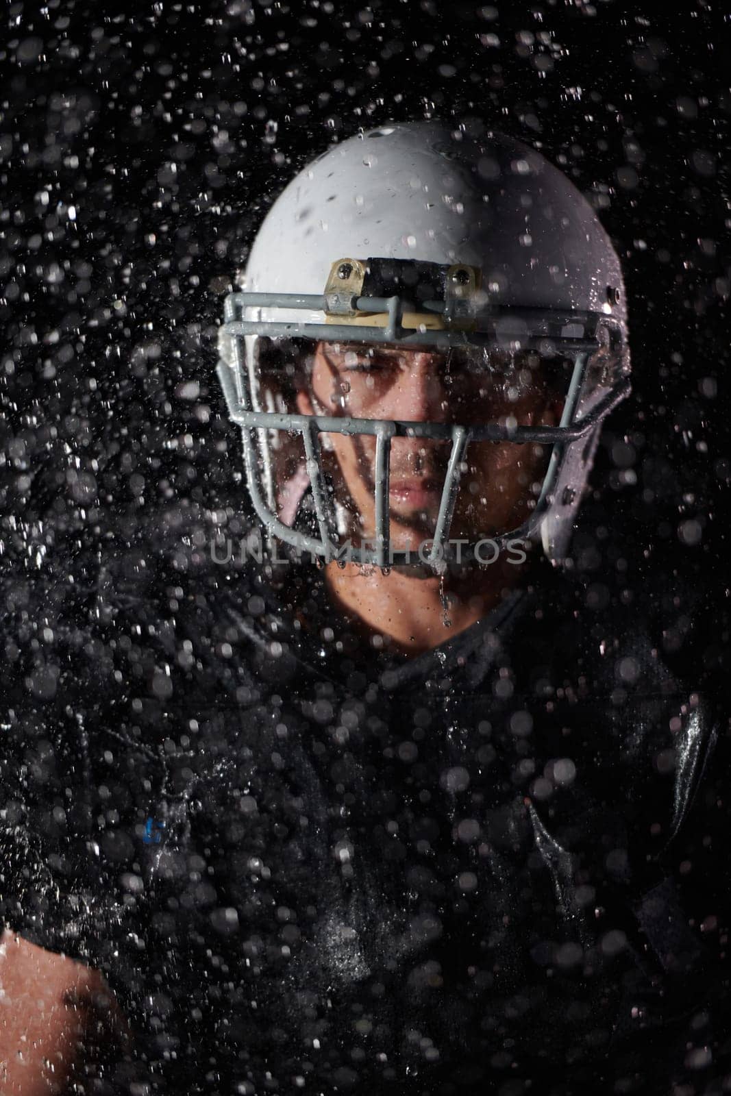 American Football Field: Lonely Athlete Warrior Standing on a Field Holds his Helmet and Ready to Play. Player Preparing to Run, Attack and Score Touchdown. Rainy Night with Dramatic Fog, Blue Light.