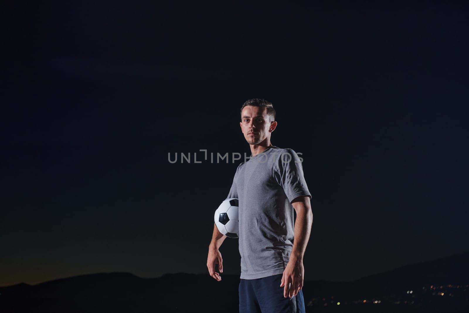 Portrait of a young handsome soccer player man on a street playing with a football ball. by dotshock