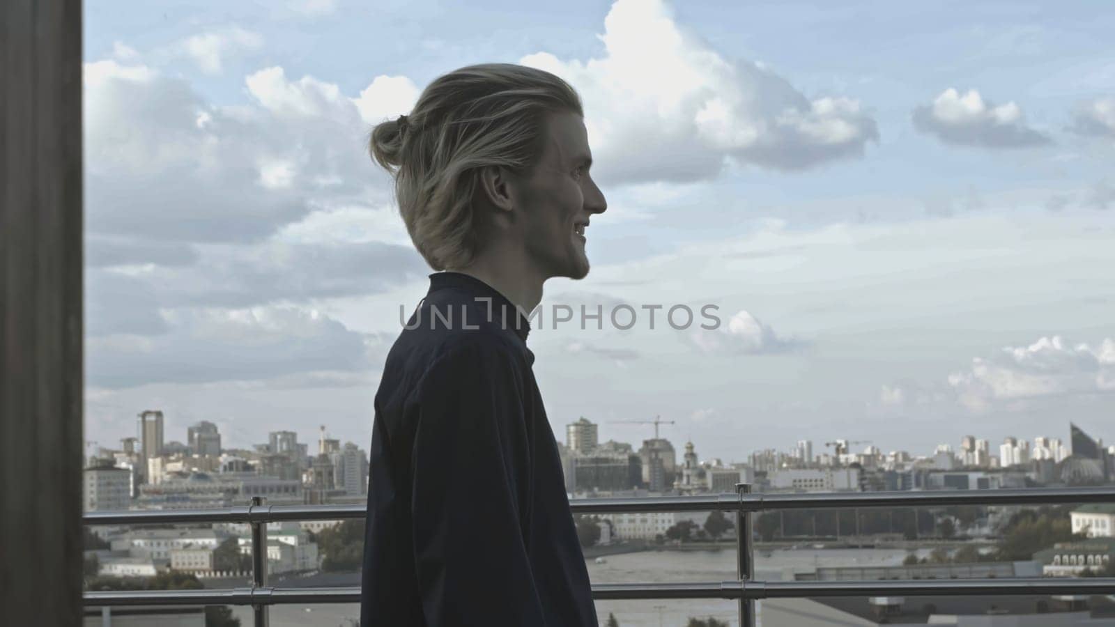 Young man on roof of building. Stock. Young man behaves strangely while on roof of building. Man on terrace of high-rise building on summer day.