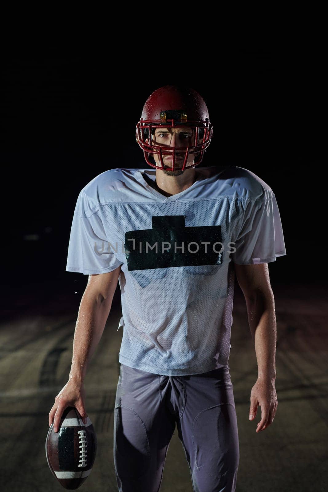 American Football Field: Lonely Athlete Warrior Standing on a Field Holds his Helmet and Ready to Play. Player Preparing to Run, Attack and Score Touchdown