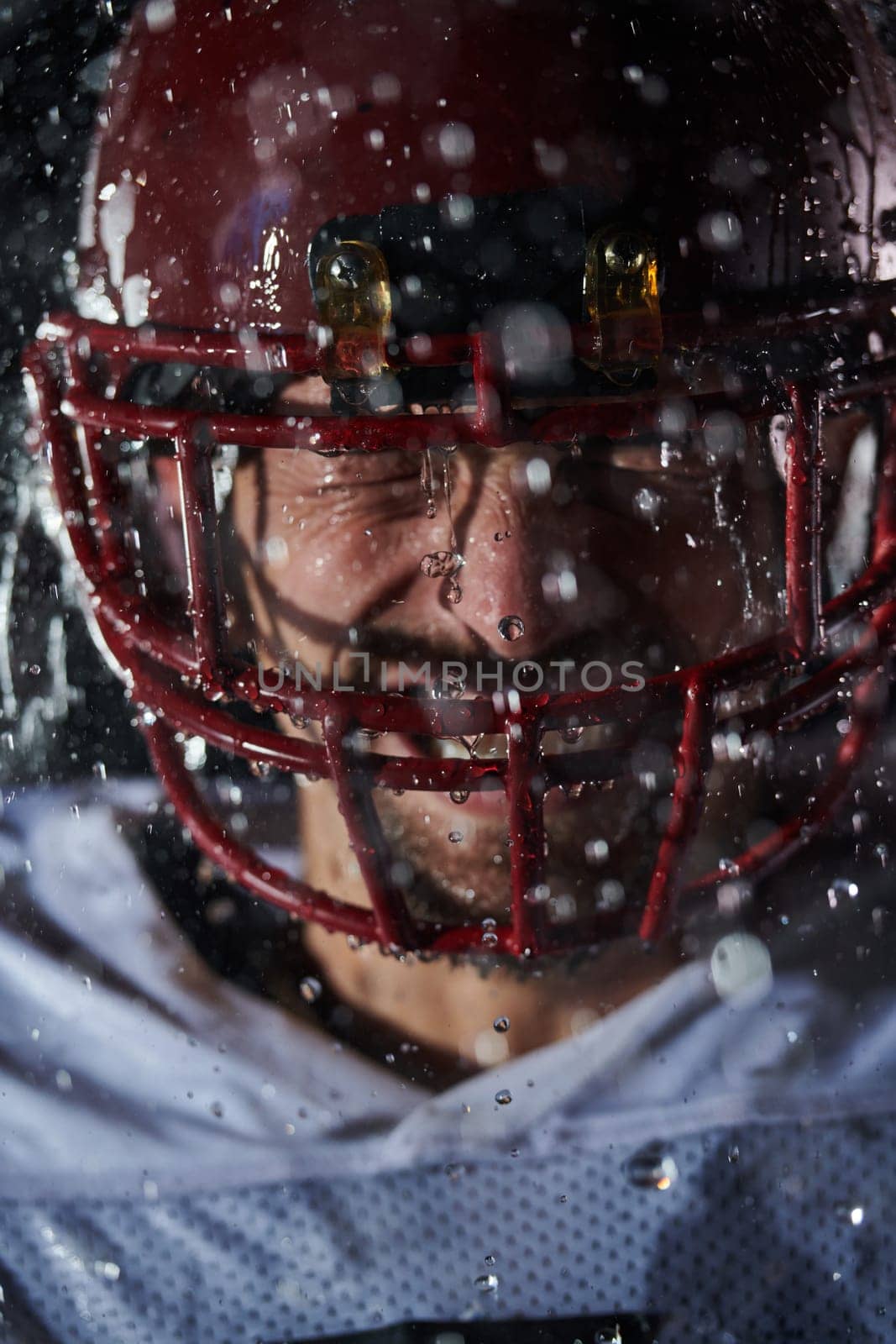 American Football Field: Lonely Athlete Warrior Standing on a Field Holds his Helmet and Ready to Play. Player Preparing to Run, Attack and Score Touchdown. Rainy Night with Dramatic Fog, Blue Light by dotshock