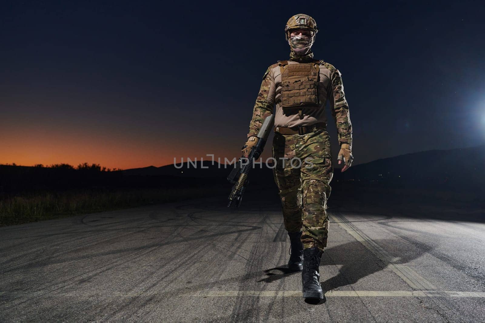 A professional soldier in full military gear striding through the dark night as he embarks on a perilous military mission.