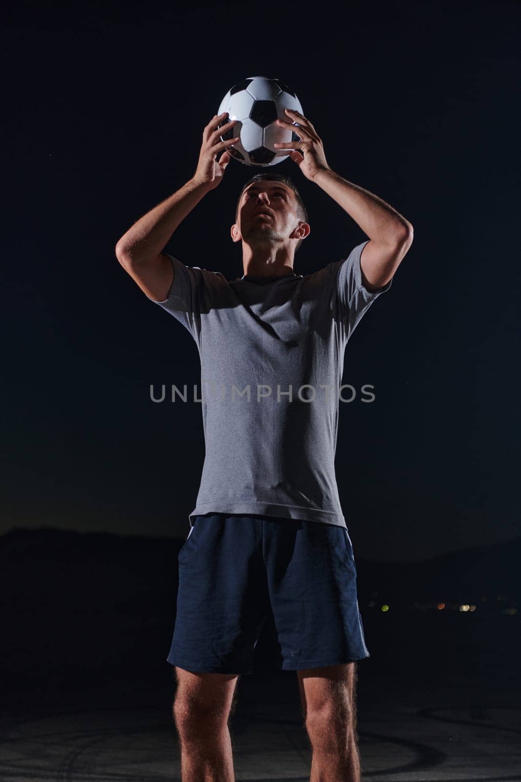 Portrait of a young handsome soccer player man on a street playing with a football ball.