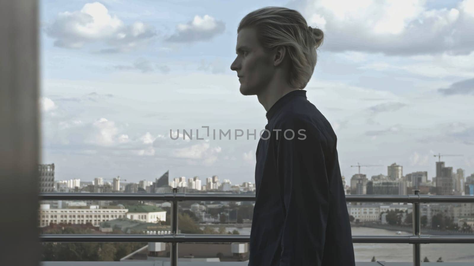 Young man on roof of building. Stock. Young man behaves strangely while on roof of building. Man on terrace of high-rise building on summer day.