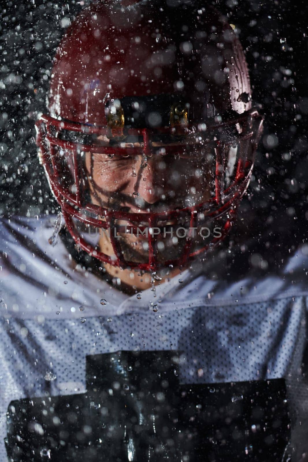 American Football Field: Lonely Athlete Warrior Standing on a Field Holds his Helmet and Ready to Play. Player Preparing to Run, Attack and Score Touchdown. Rainy Night with Dramatic Fog, Blue Light.