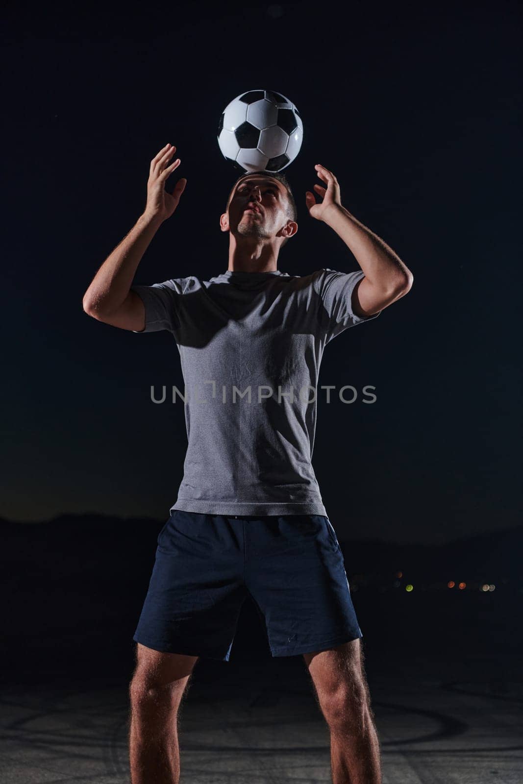 Portrait of a young handsome soccer player man on a street playing with a football ball by dotshock