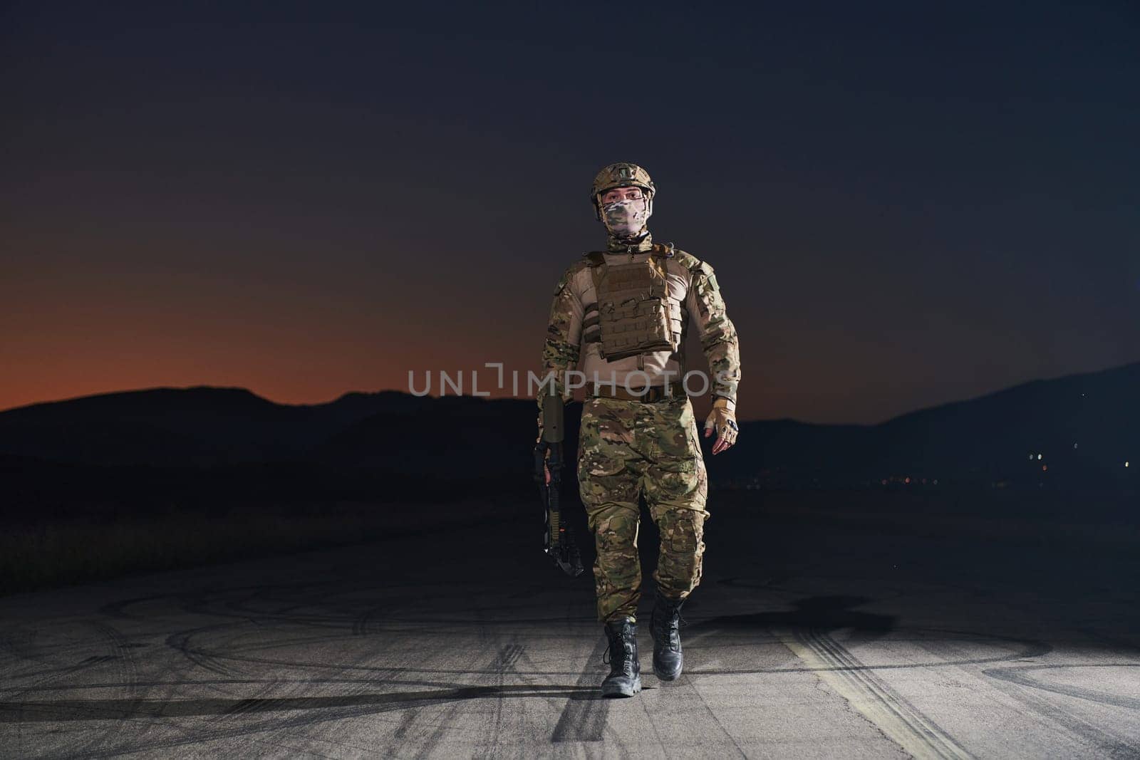 A professional soldier in full military gear striding through the dark night as he embarks on a perilous military mission.