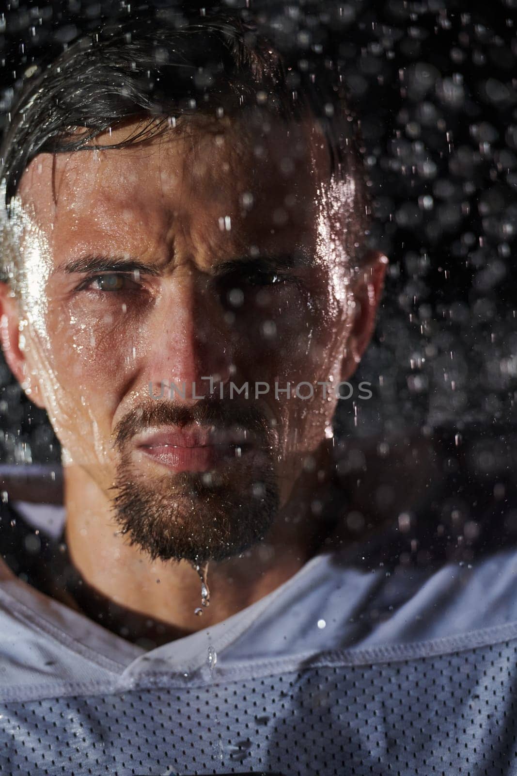 American Football Field: Lonely Athlete Warrior Standing on a Field Holds his Helmet and Ready to Play. Player Preparing to Run, Attack and Score Touchdown. Rainy Night with Dramatic Fog, Blue Light.