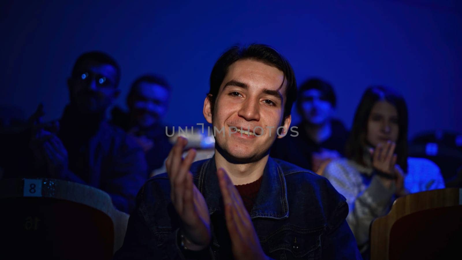 Audience at theatre or cinema. Media. Portrait of a man and silhouettes behind applauding