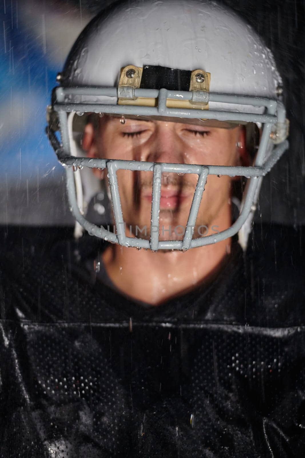 American Football Field: Lonely Athlete Warrior Standing on a Field Holds his Helmet and Ready to Play. Player Preparing to Run, Attack and Score Touchdown. Rainy Night with Dramatic Fog, Blue Light.