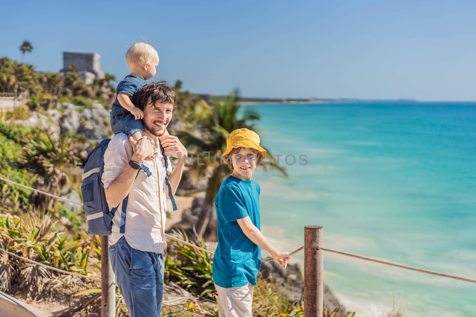 Father and two sons tourists enjoying the view Pre-Columbian Mayan walled city of Tulum, Quintana Roo, Mexico, North America, Tulum, Mexico. El Castillo - castle the Mayan city of Tulum main temple.