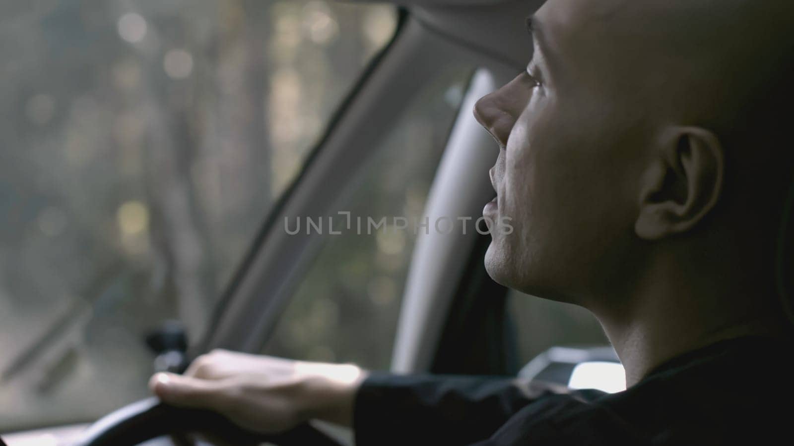 Rear view of driver driving car on summer day. Stock. View from passenger seat to driver of car. Cinematic car driving on sunny summer day.