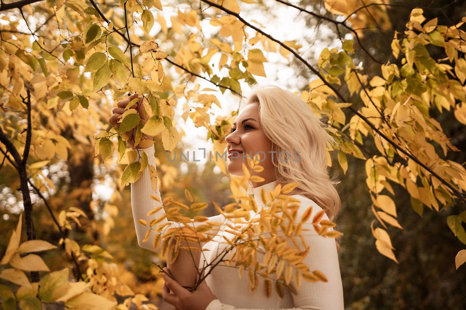 A woman is standing in a forest with leaves on the ground. She is holding a leaf in her hand. by Matiunina