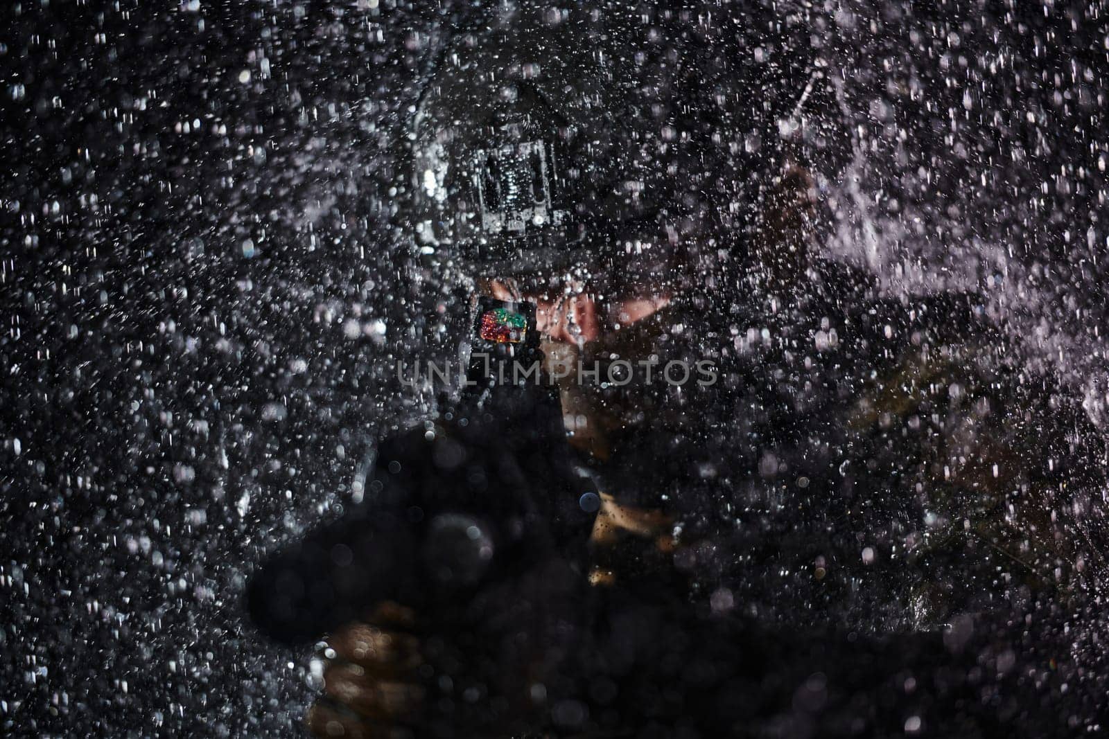 Army soldier in Combat Uniforms with an assault rifle, plate carrier and combat helmet going on a dangerous mission on a rainy night