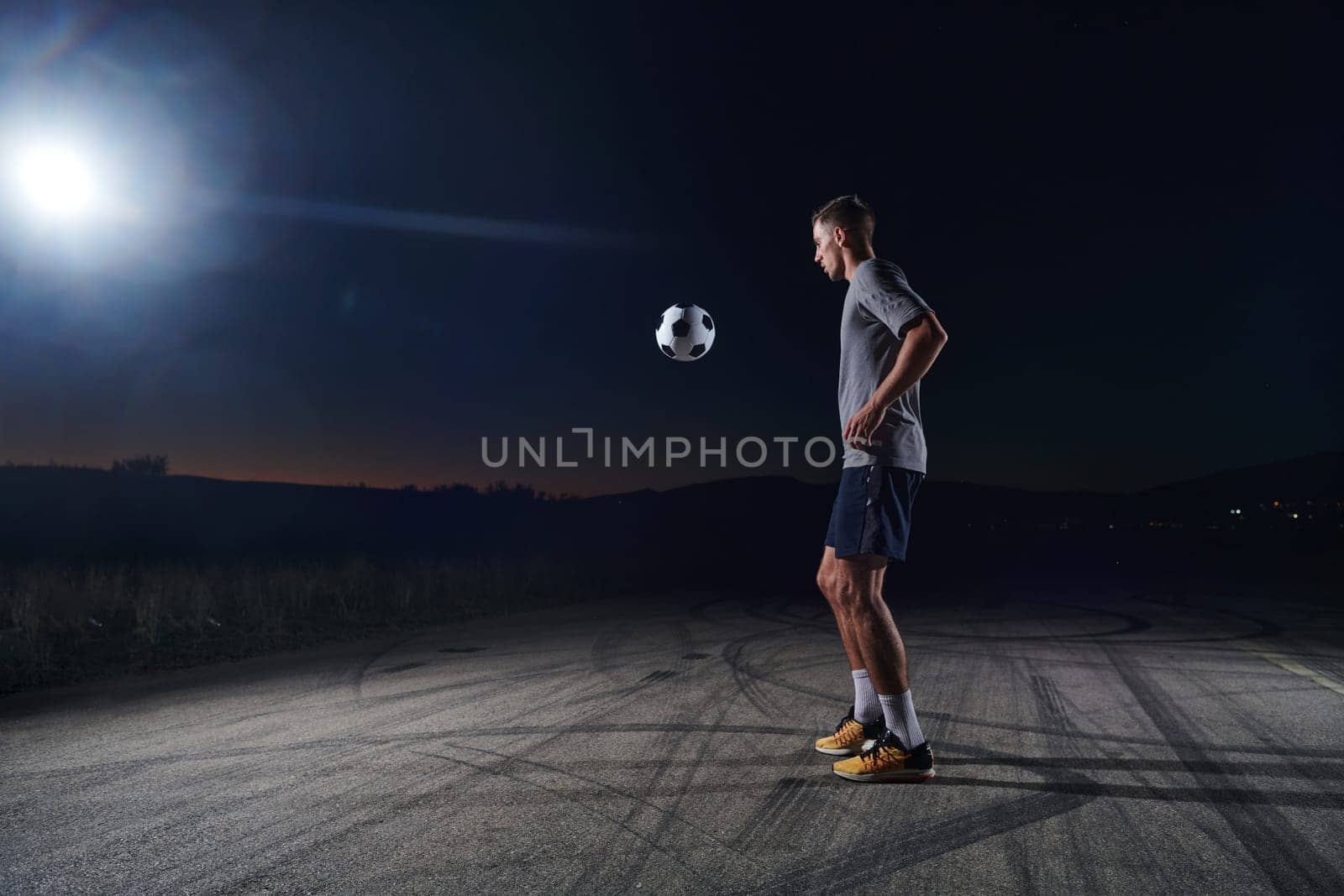 Portrait of a young handsome soccer player man on a street playing with a football ball by dotshock