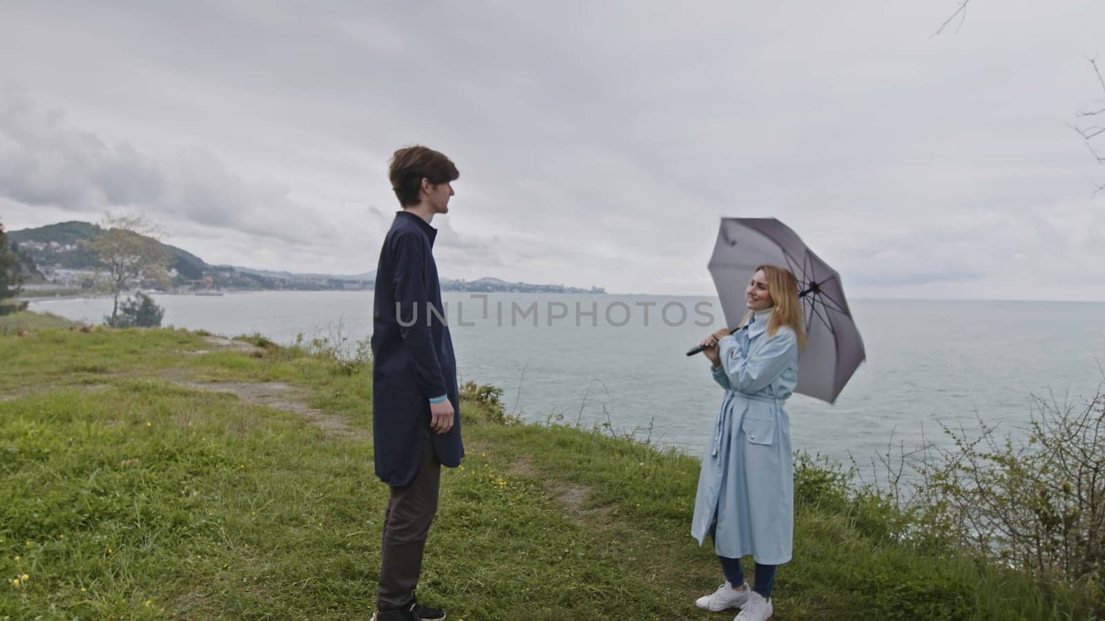 Young couple dating by the ocean shore and communicating. Stock clip. Man and woman spend time outdoors on a cold windy day