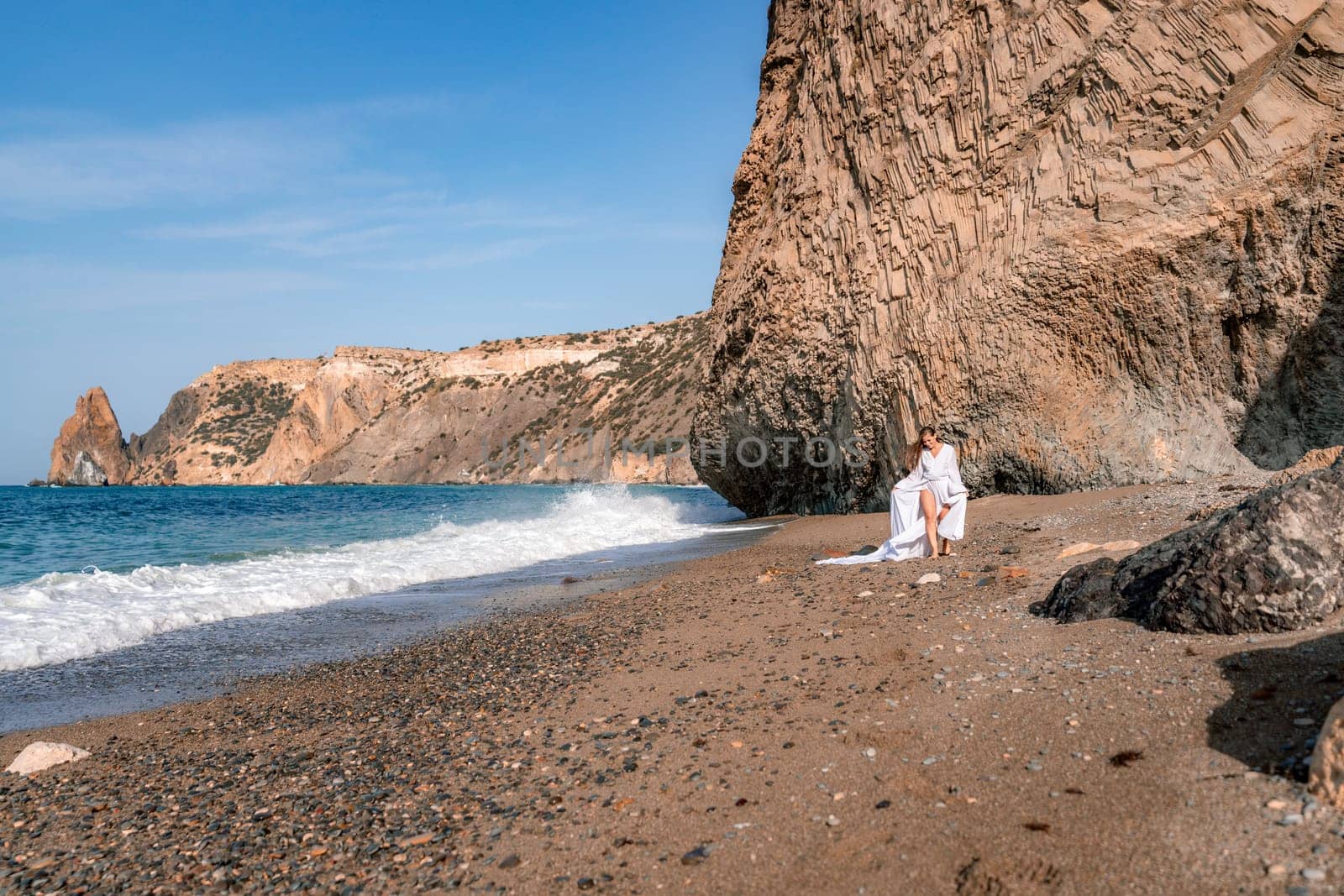 Woman beach white dress flying on Wind. Summer Vacation. A happy woman takes vacation photos to send to friends. by Matiunina