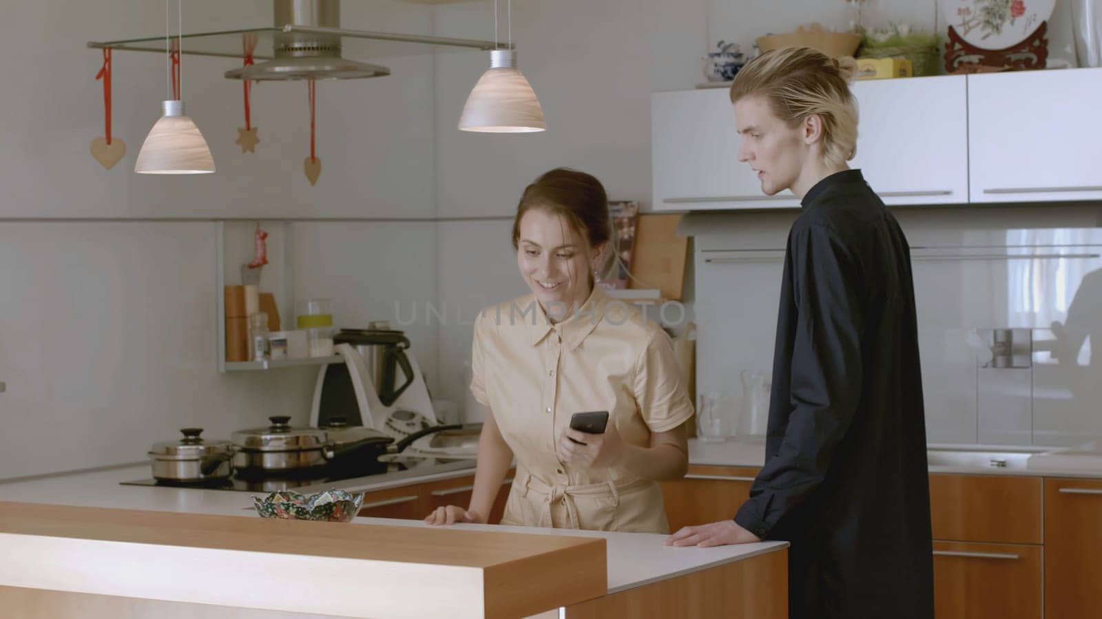 Man wants to talk to woman with headphones on. Stock. Woman with headphones ignores man. Man wants to talk to woman who is busy in kitchen.