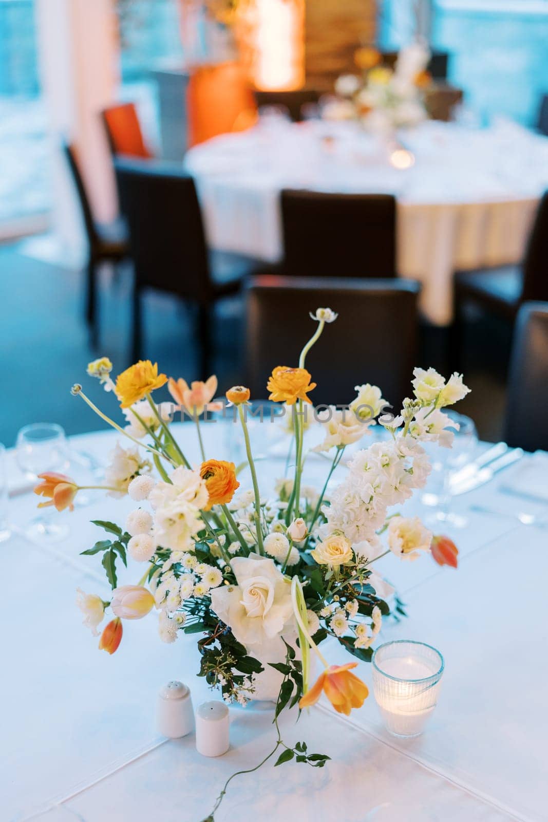 Colorful bouquet of flowers stands near candles on a laid festive table. High quality photo