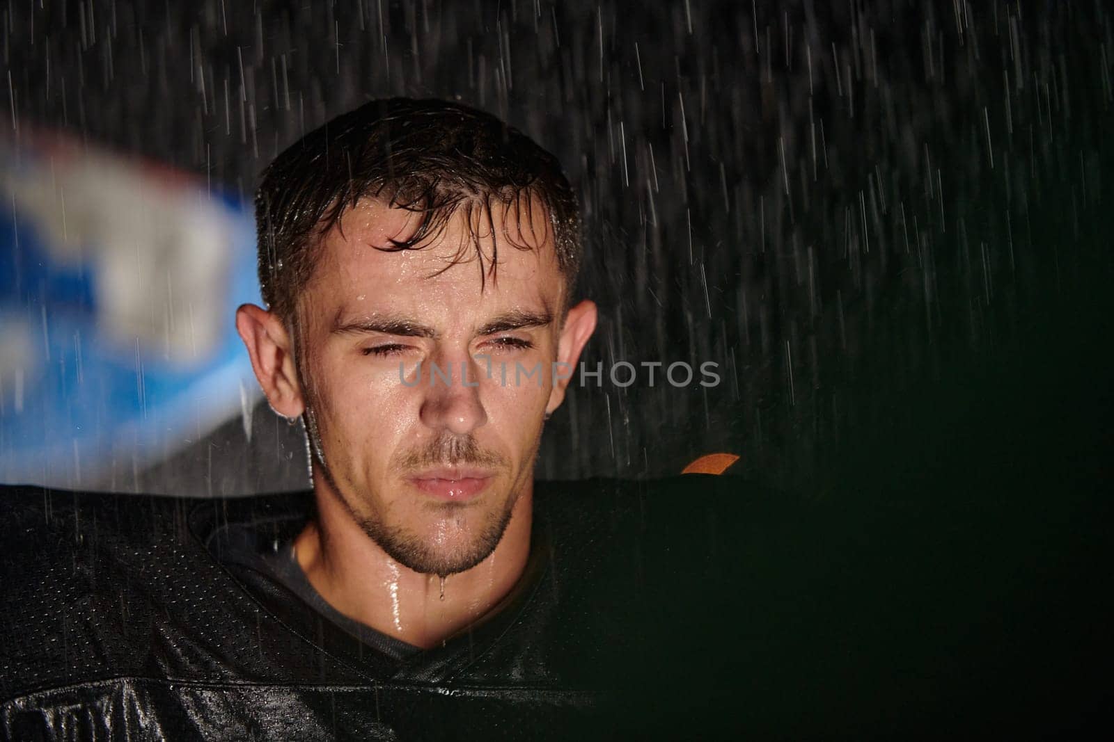 American Football Field: Lonely Athlete Warrior Standing on a Field Holds his Helmet and Ready to Play. Player Preparing to Run, Attack and Score Touchdown. Rainy Night with Dramatic Fog, Blue Light.