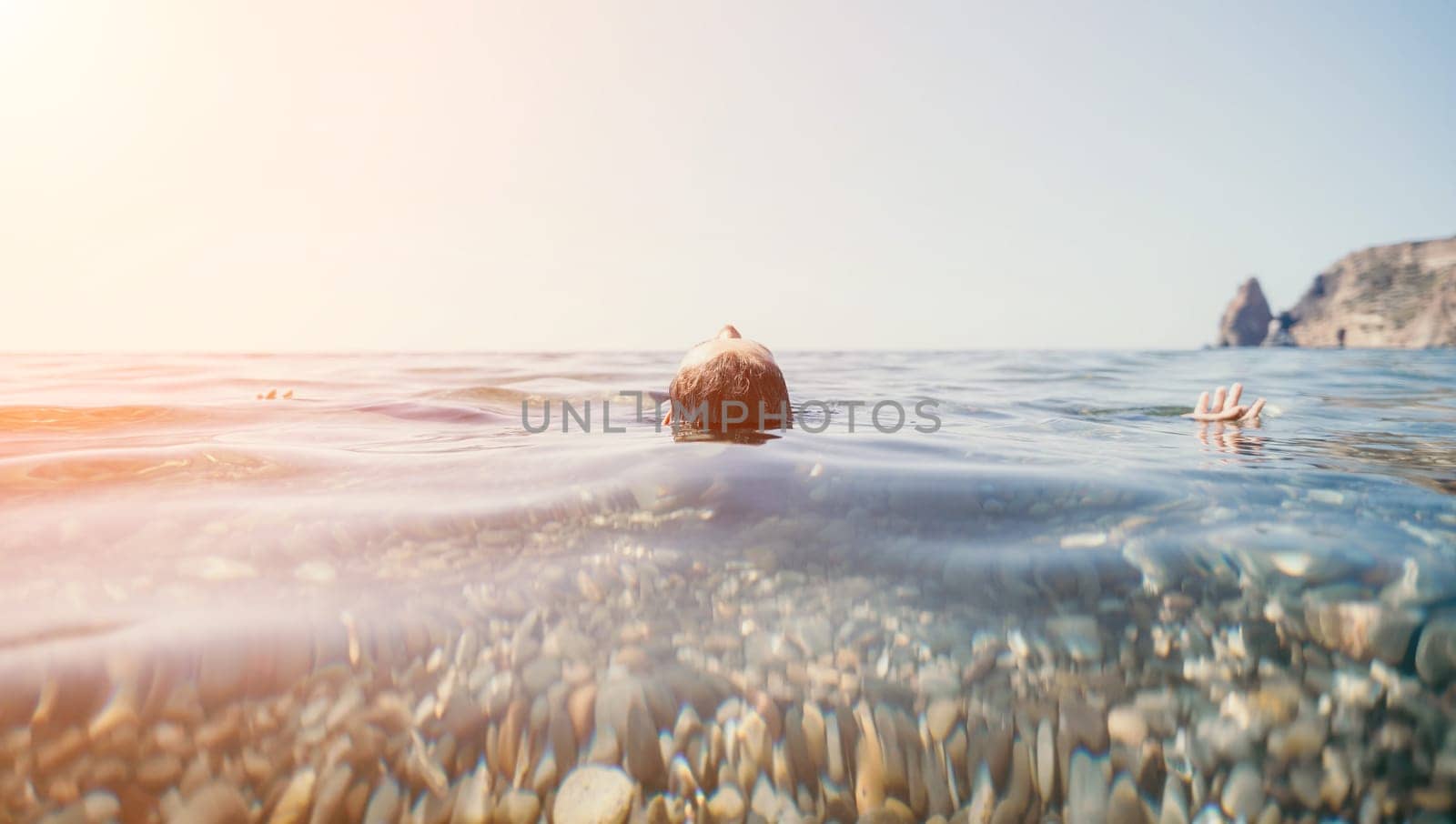 Woman swimming in sea at sunset, float on calm water back view. Concept of body image and fitness, enjoying a serene beach. Happy woman with perfect fit body enjoys sea beach by panophotograph