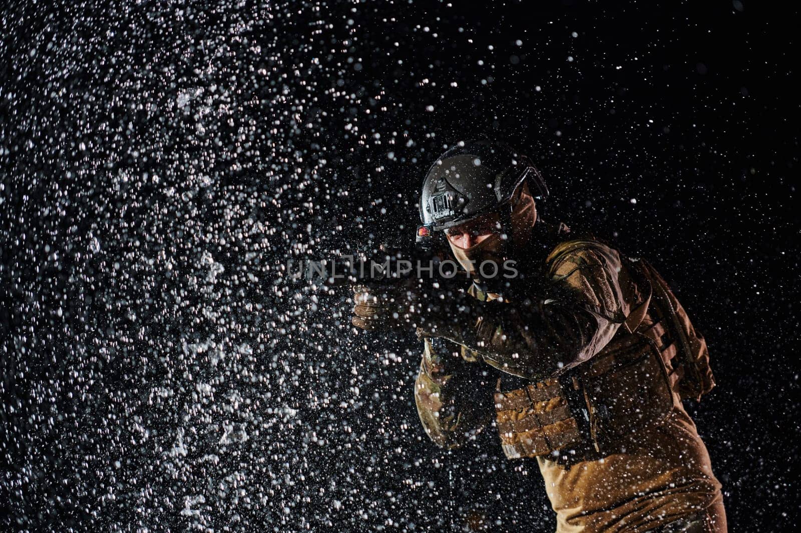 Army soldier in Combat Uniforms with an assault rifle, plate carrier and combat helmet going on a dangerous mission on a rainy night