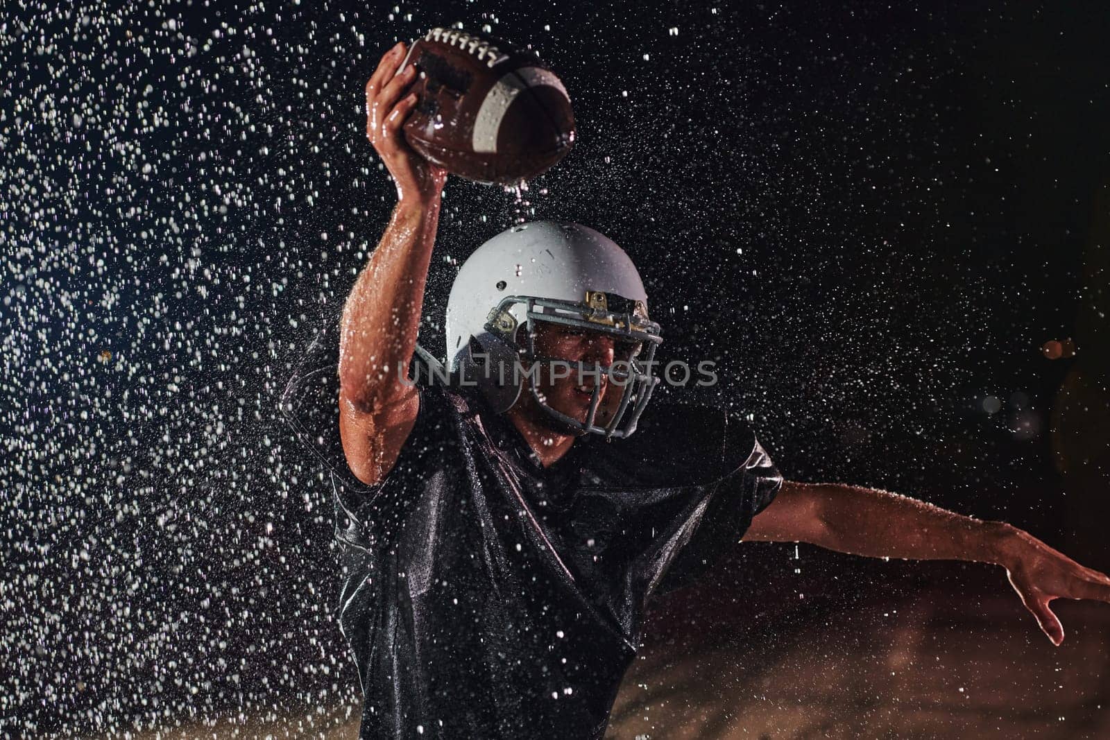 American Football Field: Lonely Athlete Warrior Standing on a Field Holds his Helmet and Ready to Play. Player Preparing to Run, Attack and Score Touchdown. Rainy Night with Dramatic Fog, Blue Light.