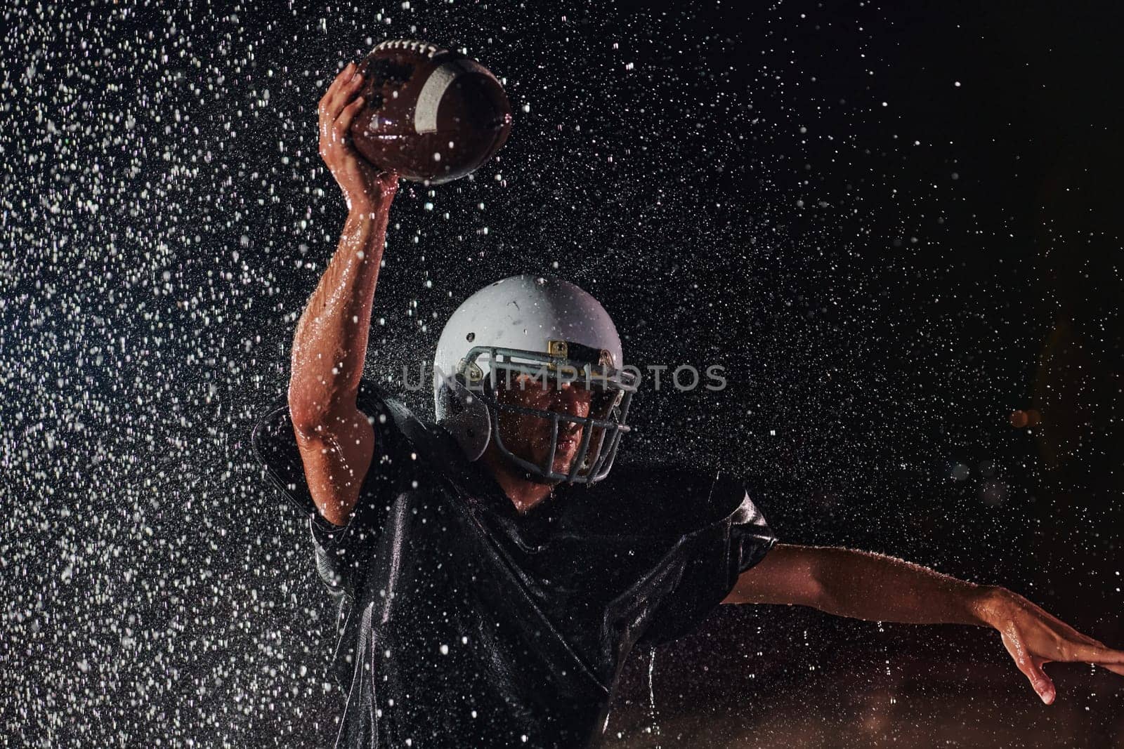 American Football Field: Lonely Athlete Warrior Standing on a Field Holds his Helmet and Ready to Play. Player Preparing to Run, Attack and Score Touchdown. Rainy Night with Dramatic Fog, Blue Light.