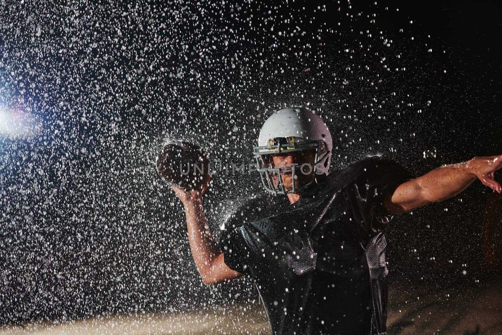 American Football Field: Lonely Athlete Warrior Standing on a Field Holds his Helmet and Ready to Play. Player Preparing to Run, Attack and Score Touchdown. Rainy Night with Dramatic Fog, Blue Light.