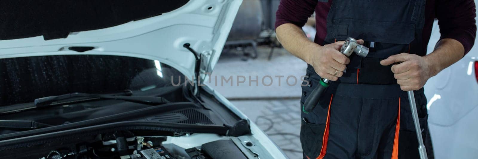 banner Car service. An auto mechanic is standing near the car with a tool in his hands. Vehicle technical inspection.