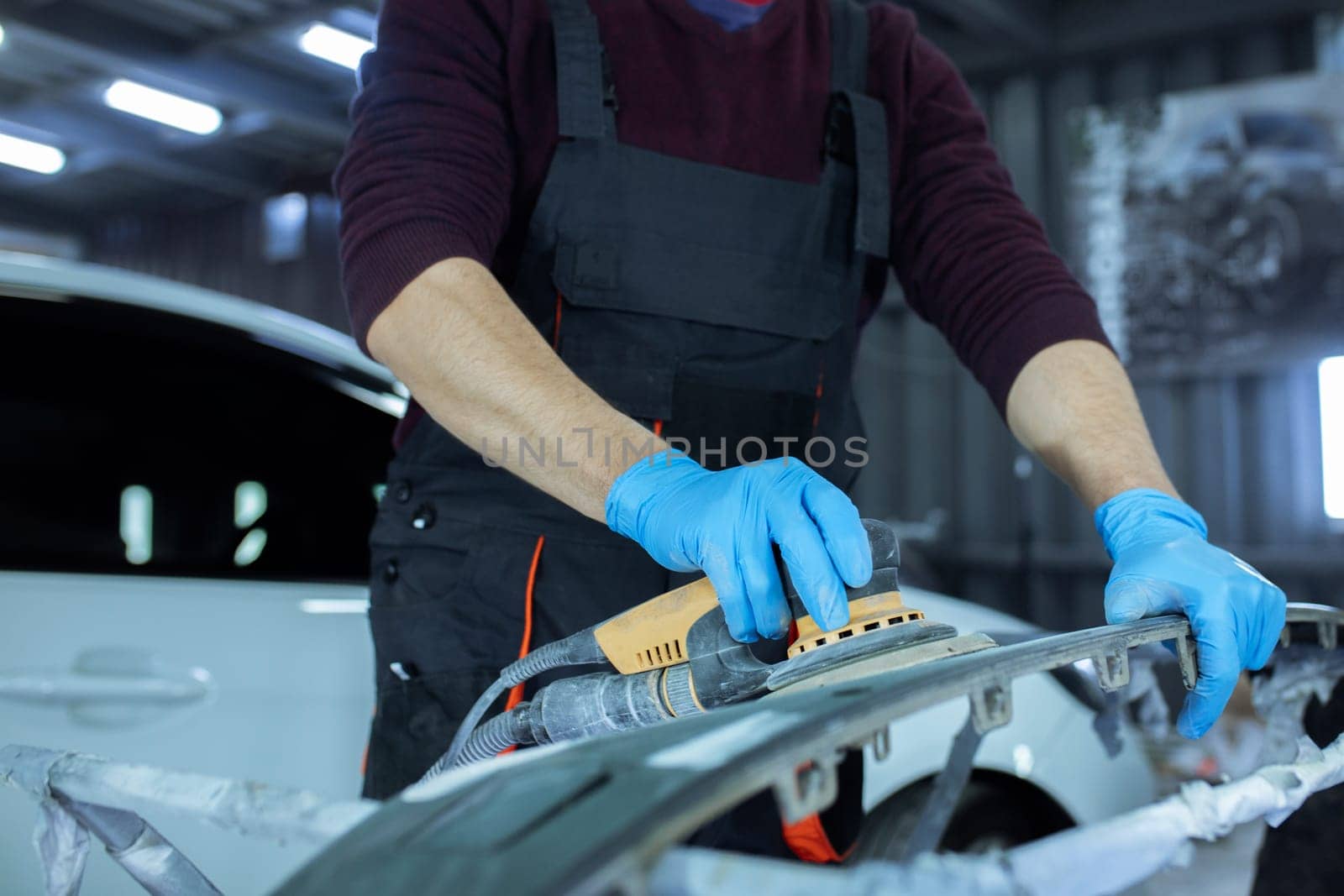 Repairing car body by puttying close up work after the accident by working sanding primer before painting. , The mechanic repair the car , Using plastic putty ,Prepare surface for spray painting