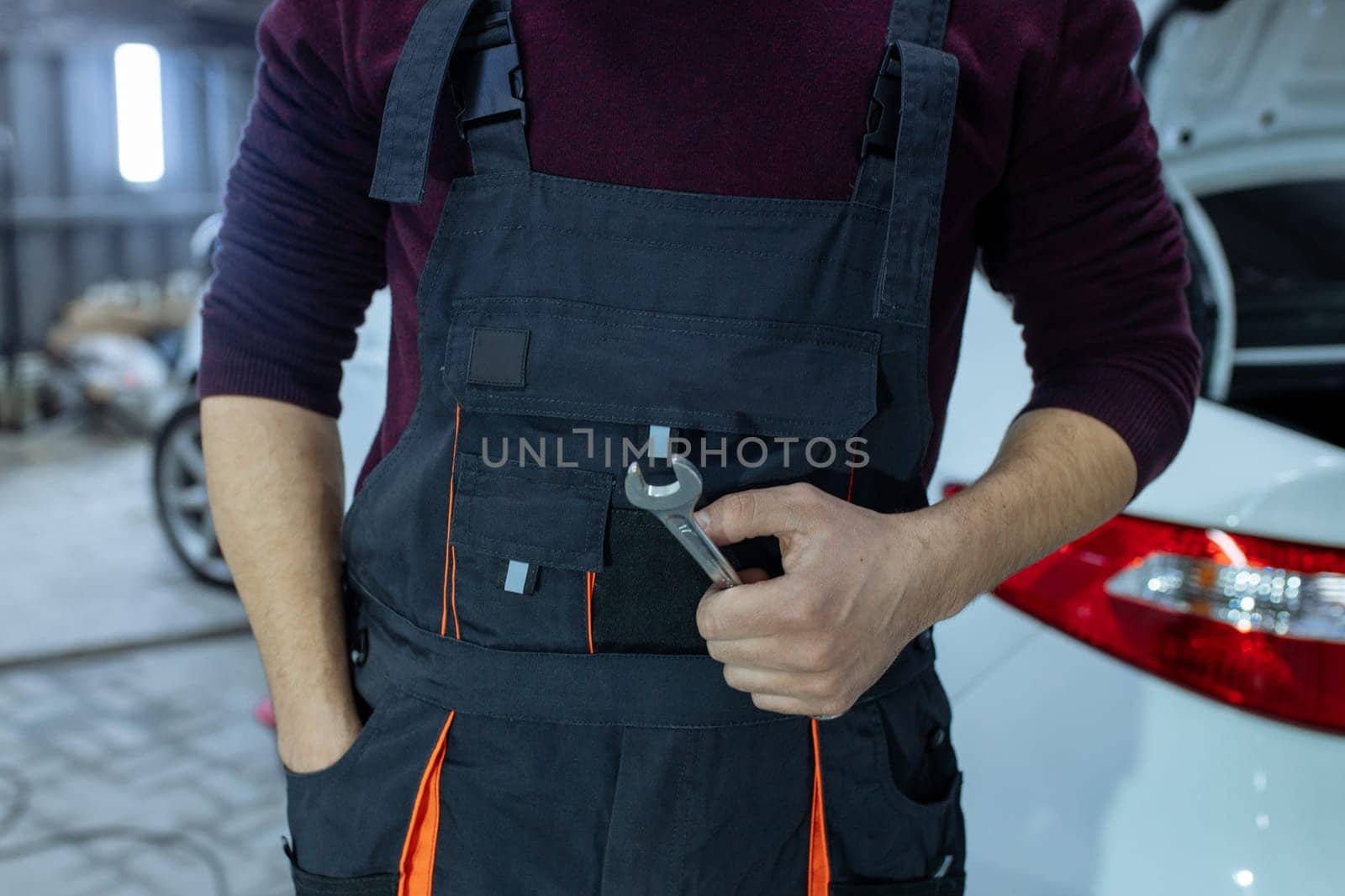 Car service. An auto mechanic is standing near the car with a tool in his hands. Vehicle technical inspection.