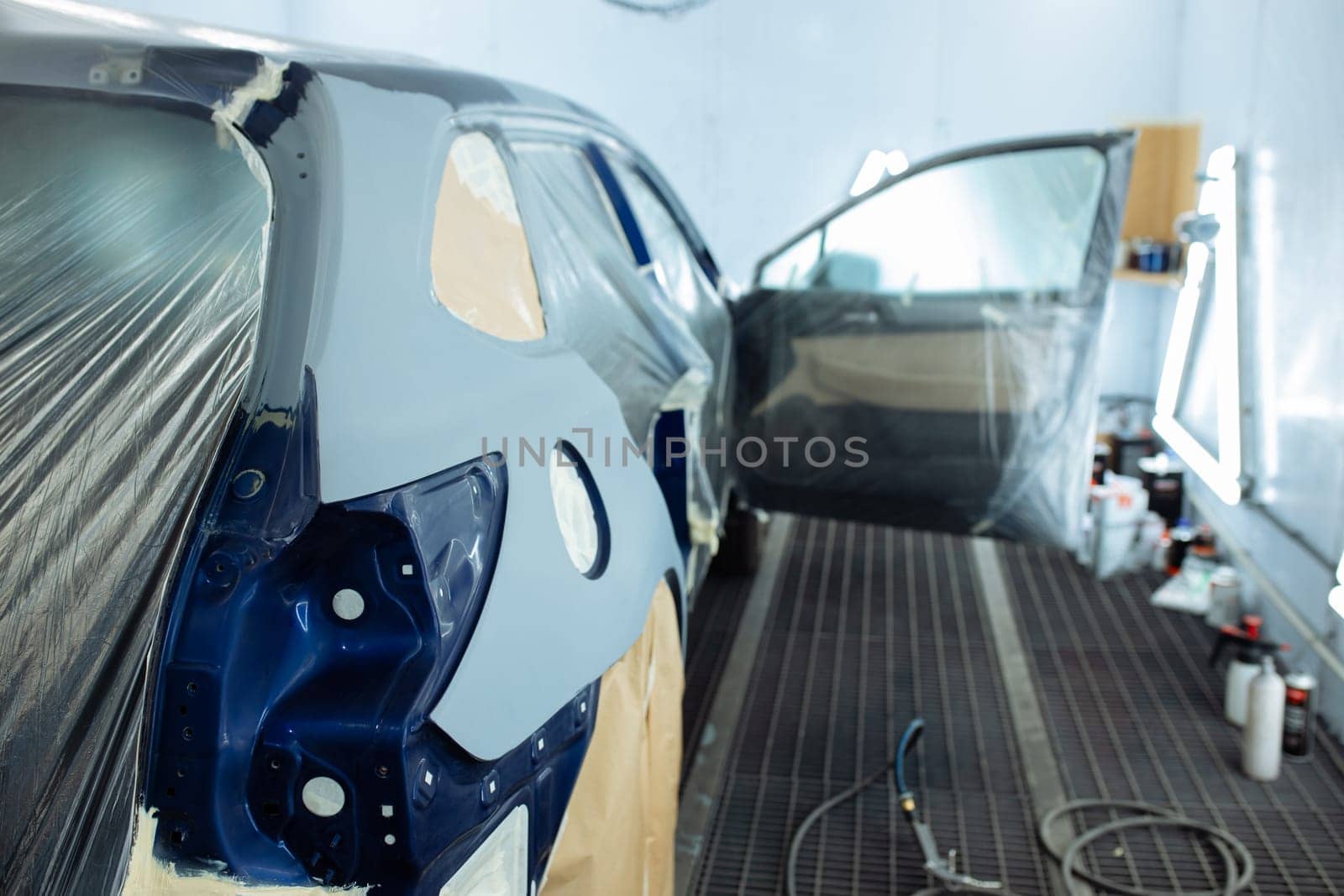 automobile repairman painter hand in protective glove with airbrush pulverizer painting car body in paint chamber