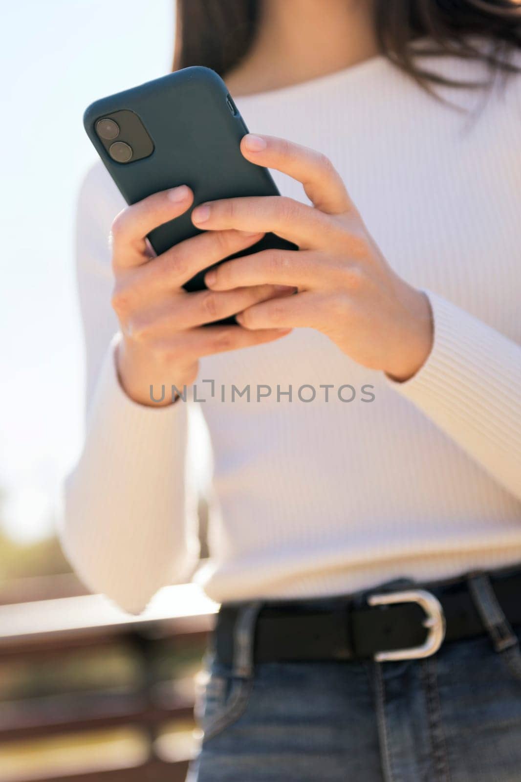 hands of an unrecognizable caucasian woman using mobile phone outdoors, concept of technology of communication and modern lifestyle