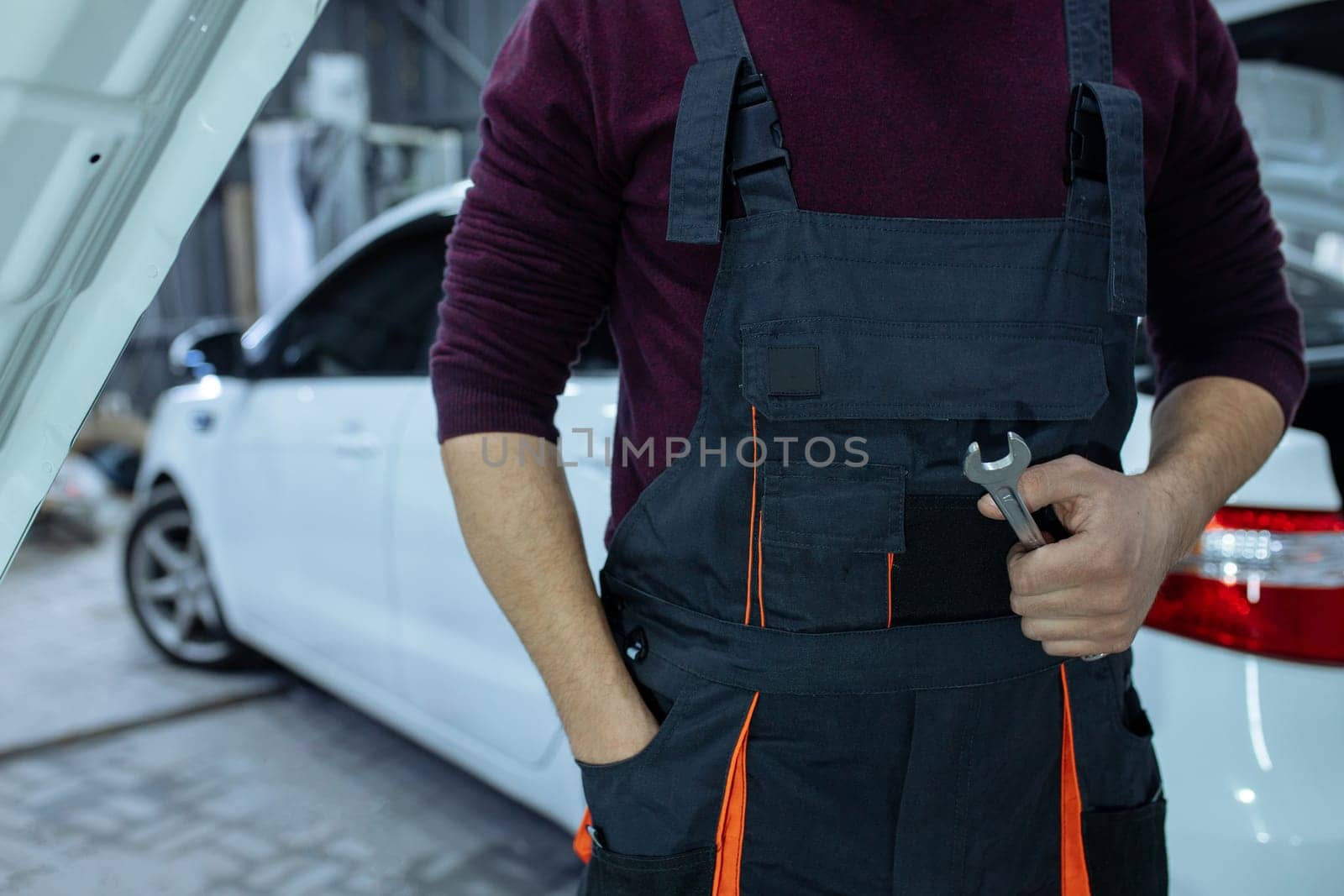 Car service. An auto mechanic is standing near the car with a tool in his hands. Vehicle technical inspection.