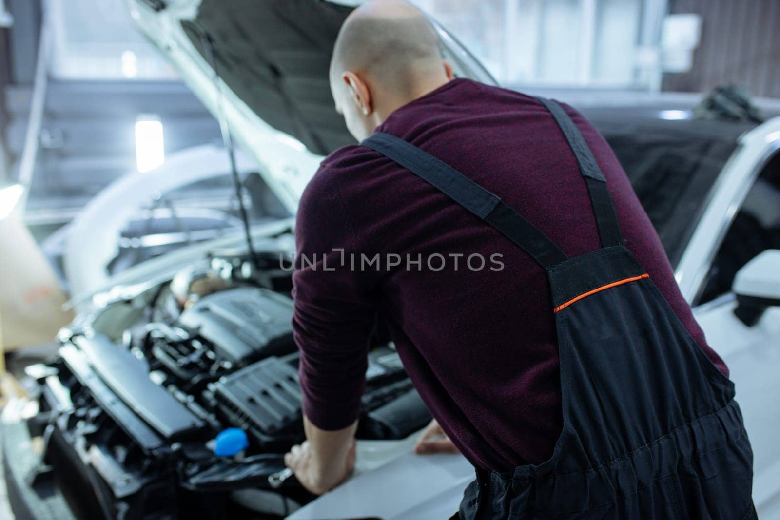 A male automech is inspecting the car's engine. Car service and car repair.