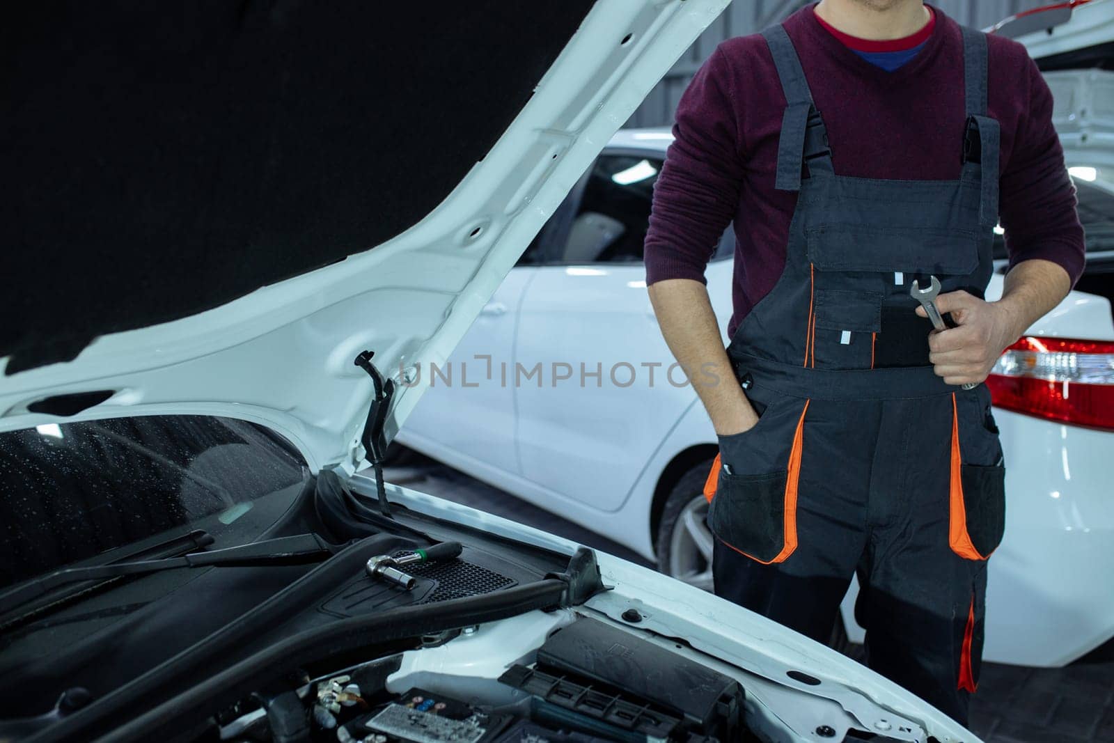 Car service. An auto mechanic is standing near the car with a tool in his hands. Vehicle technical inspection.