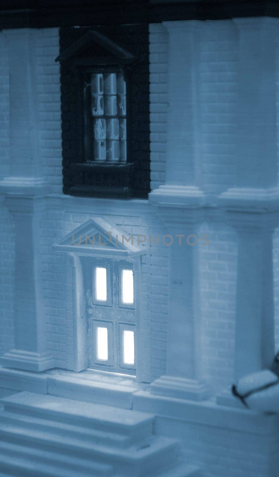 Model of building with white and black color, windows with light shining, created by 3D printer from molten plastic. Prototype printed on 3D printer brick building with columns and glowing windows.