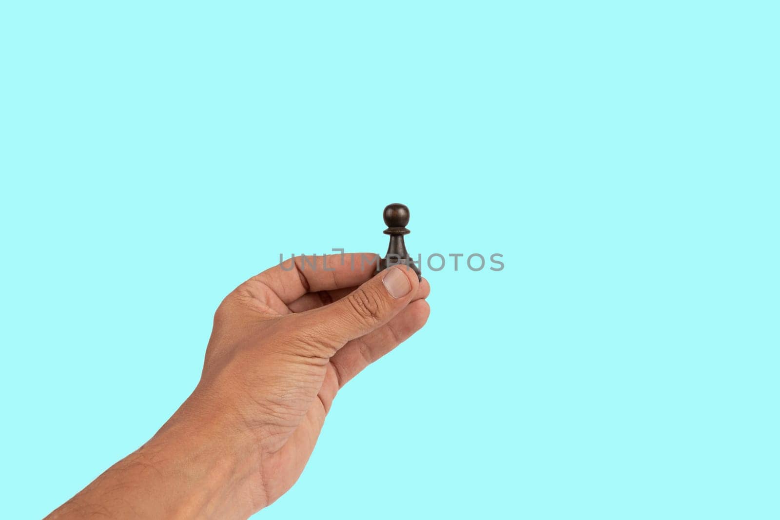 Isolated hand holding a chess figure on cyan background. High quality photo