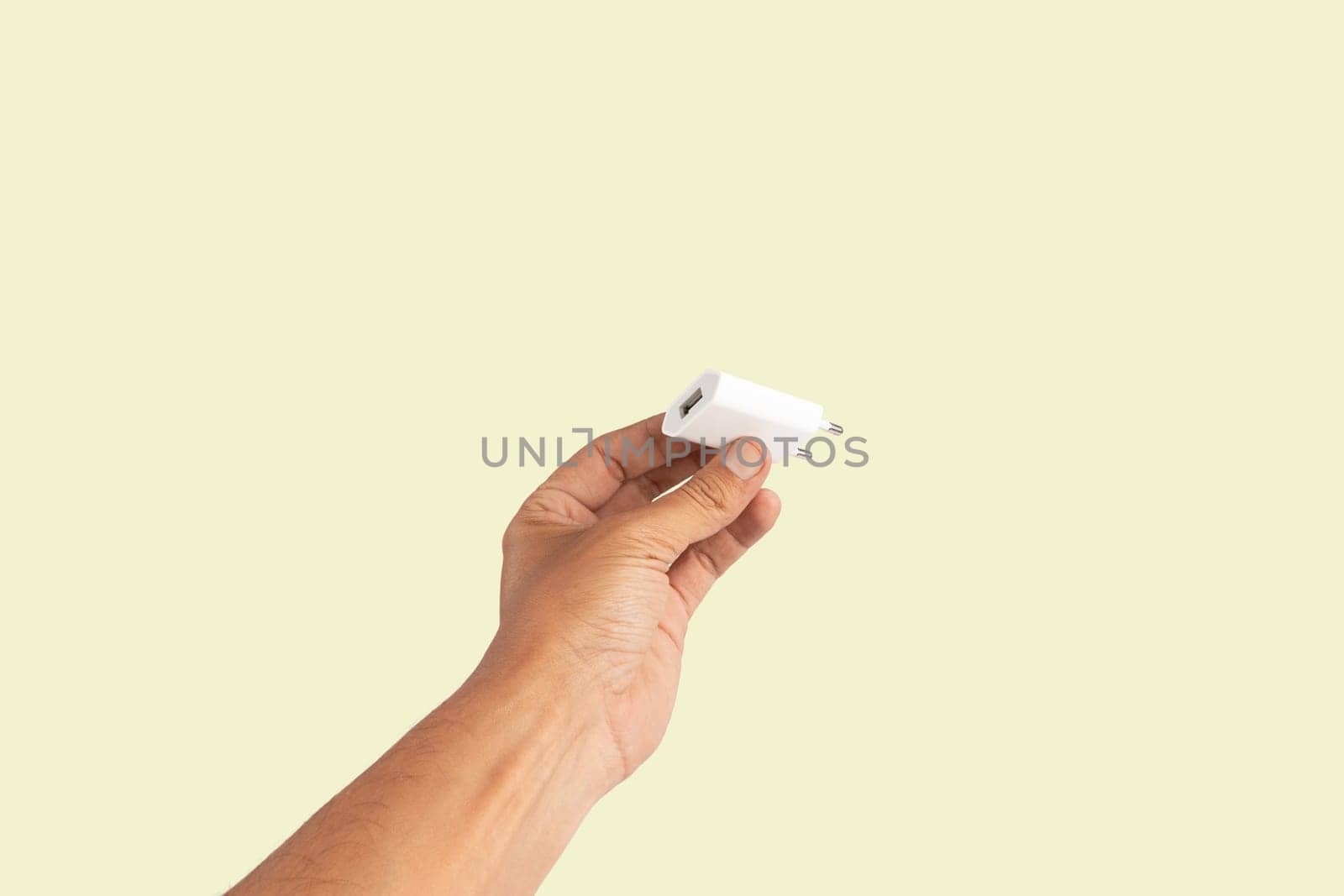 Black male hand holding a USB charger plug isolated on green background. High quality photo