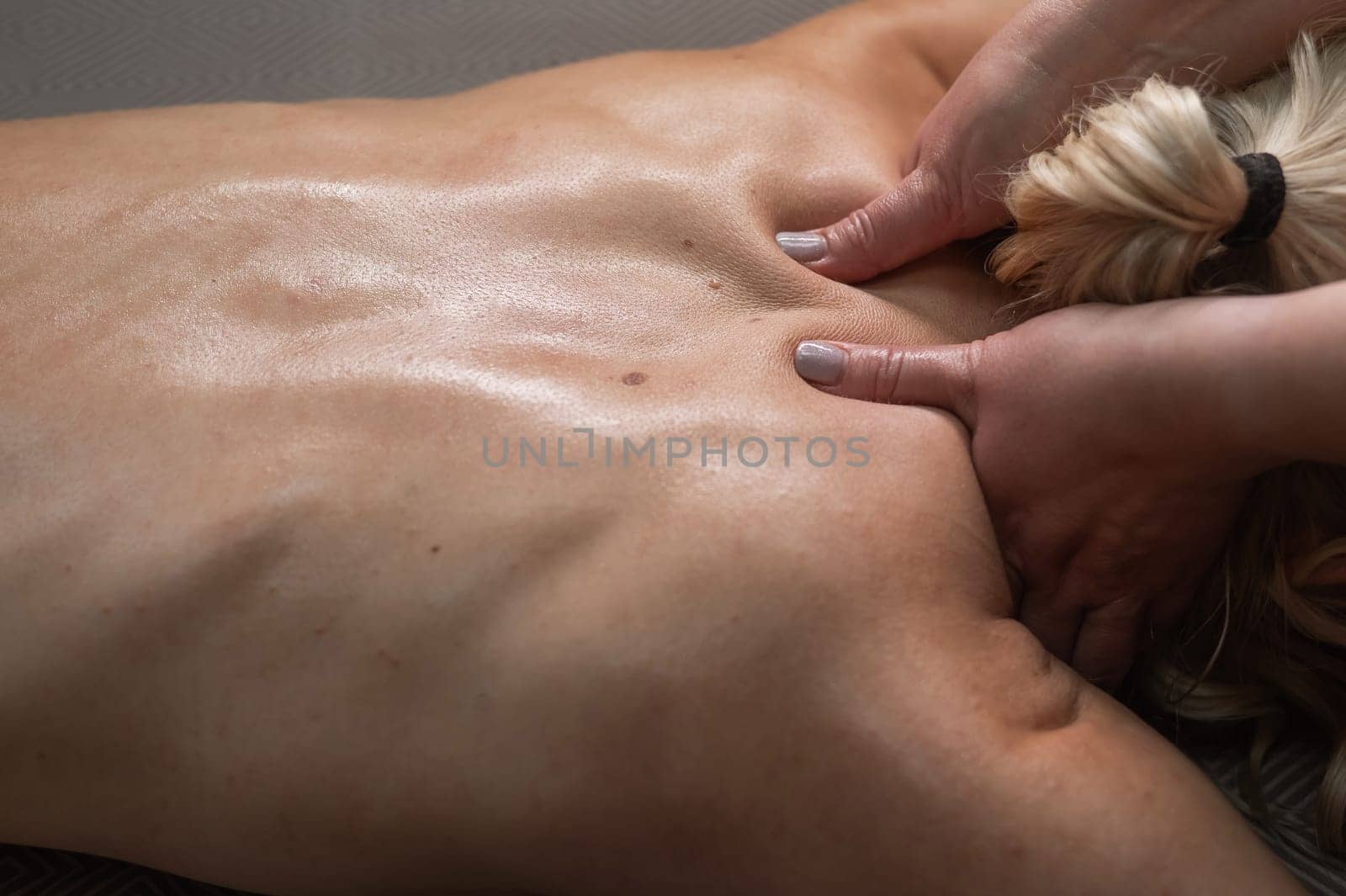 A woman undergoing a massage of the cervical-collar area