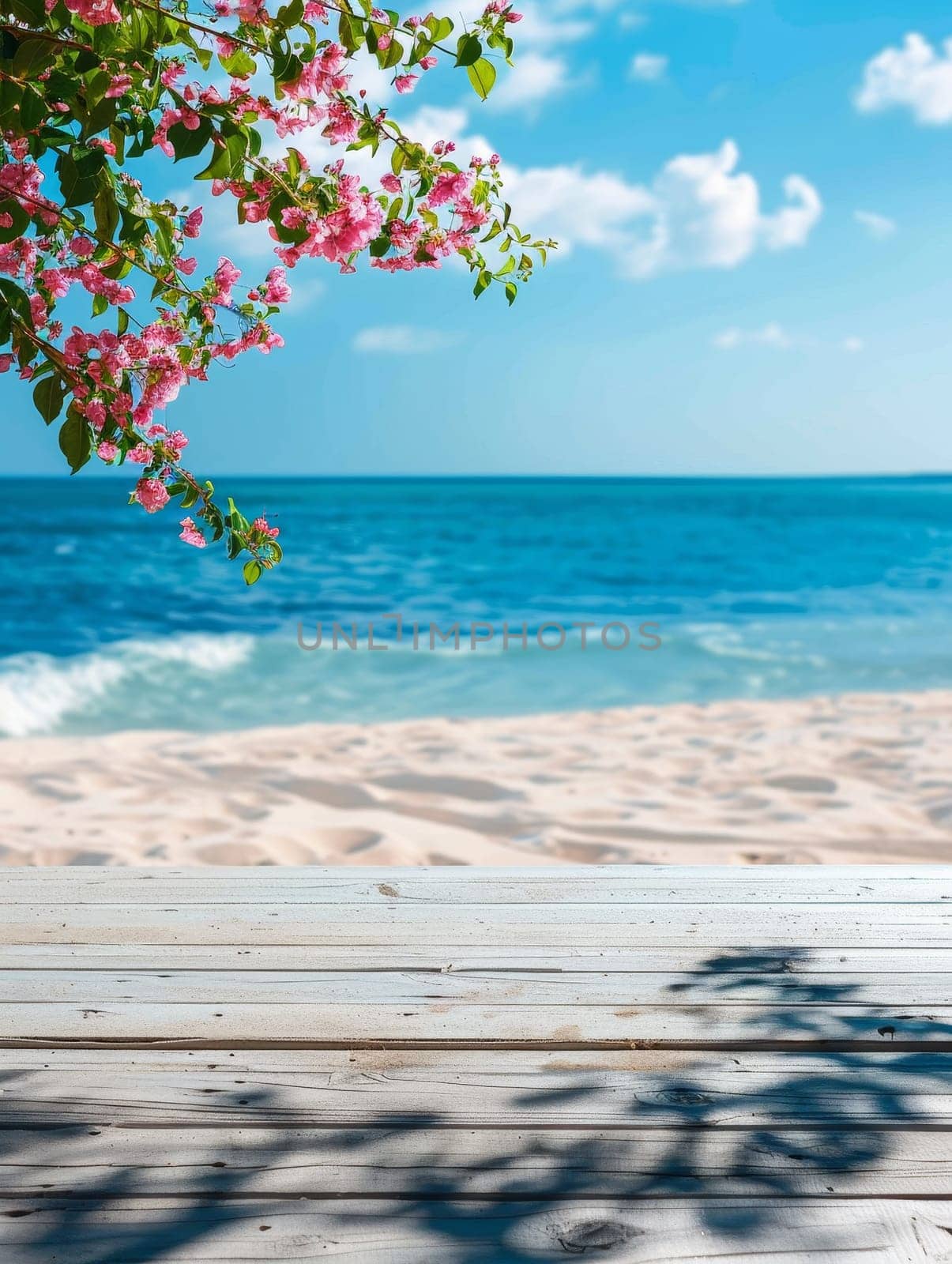 Overlooking a tranquil beach, a branch with delicate pink blossoms frames a pristine sea under a clear blue sky. The wooden deck's shadow adds depth to the serene setting by sfinks