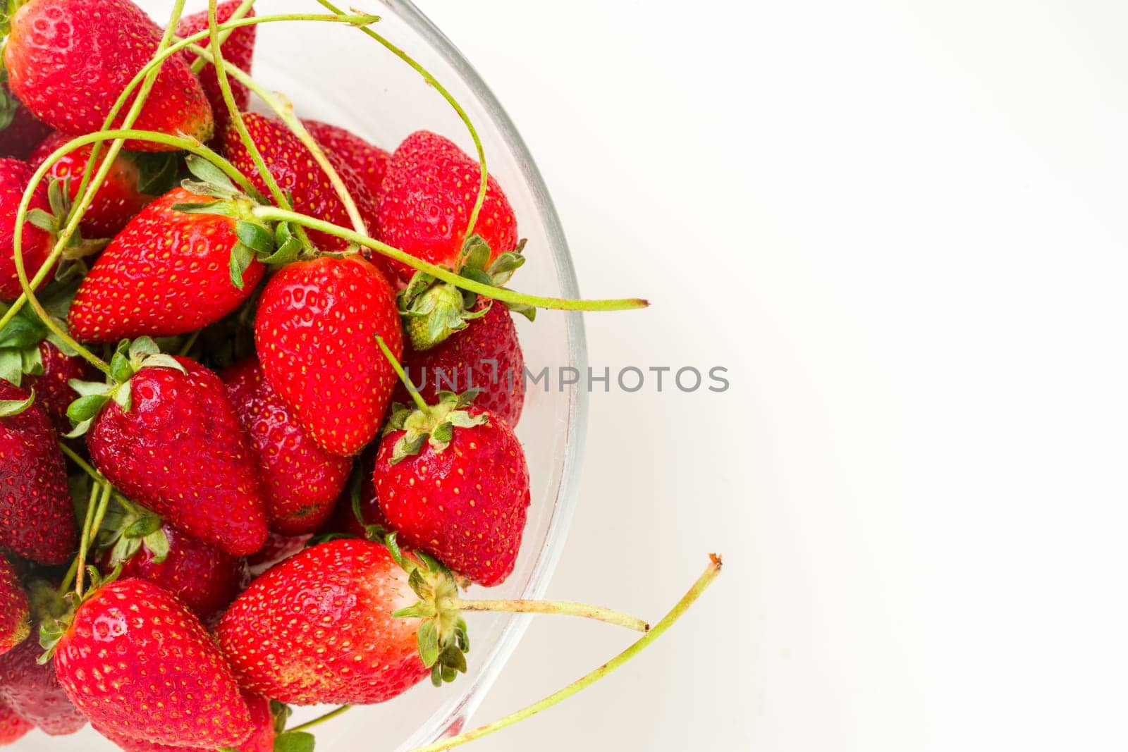 Top view of strawberries in glass bowl on white background by Sonat
