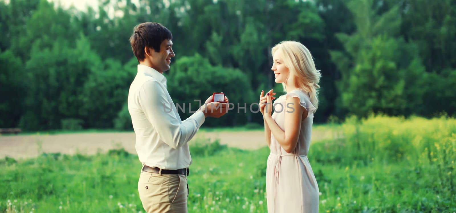 Wedding happy lovely young couple, man proposing a ring to his beloved woman outdoors in summer park by Rohappy