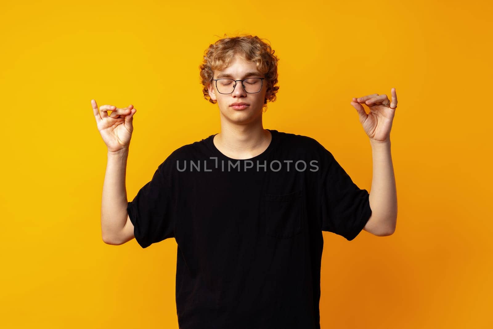 Handsome blonde man over yellow background in zen pose close up