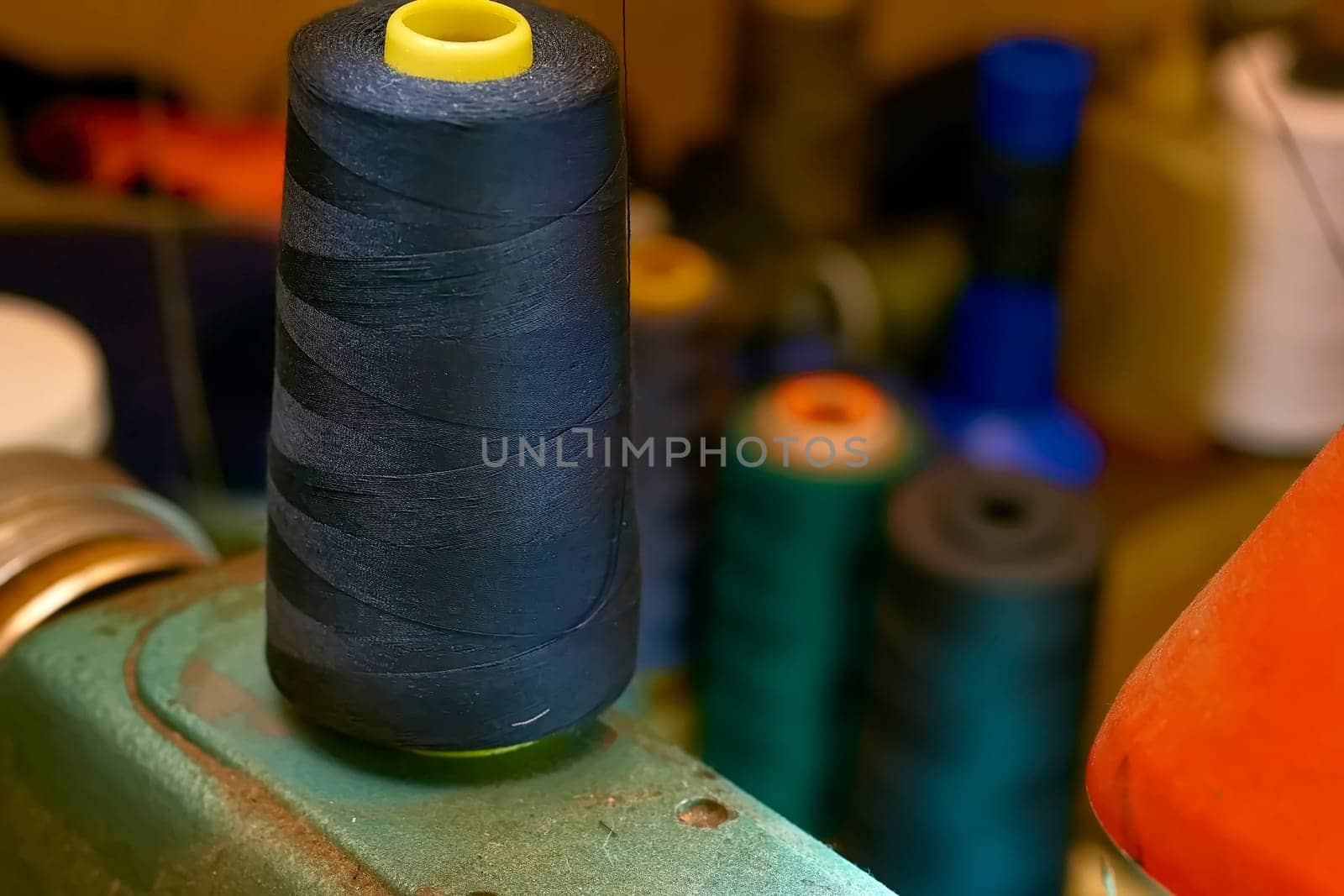 A spool of black thread on an old sewing machine in a tailor's workshop by jovani68