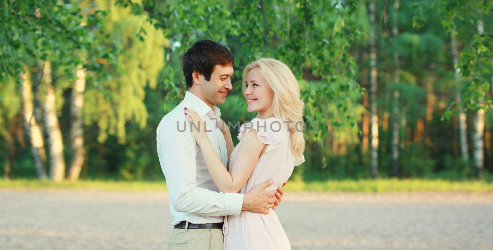 Portrait of beautiful happy smiling young couple in love together hugging in green summer park